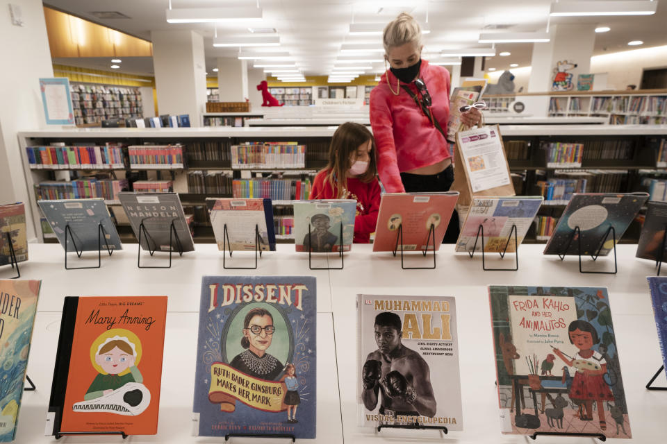 Zoe Slavin and her mother, Julie, browse for books in the children's section of the Stavros Niarchos Foundation Library, Tuesday, June 1, 2021 in New York. The city's central circulation library, closed for renovations in 2017, fully reopens today. It was previously called the Mid-Manhattan Library. (AP Photo/Mark Lennihan)