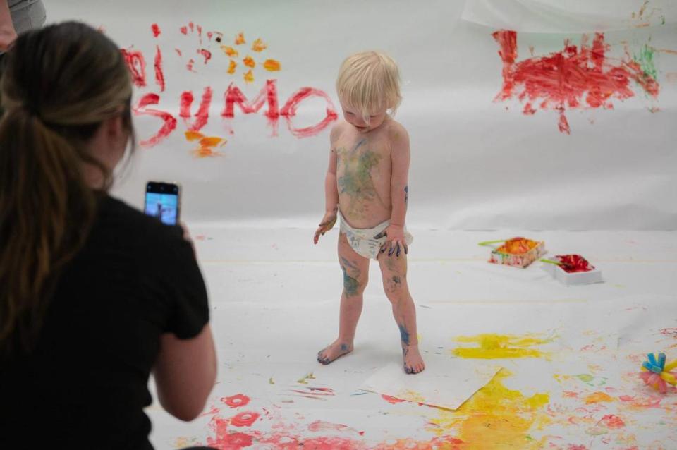 One-year-old Lucy Hoelting strikes a pose for a photo after participating in the artistic process at the baby paint crawl.