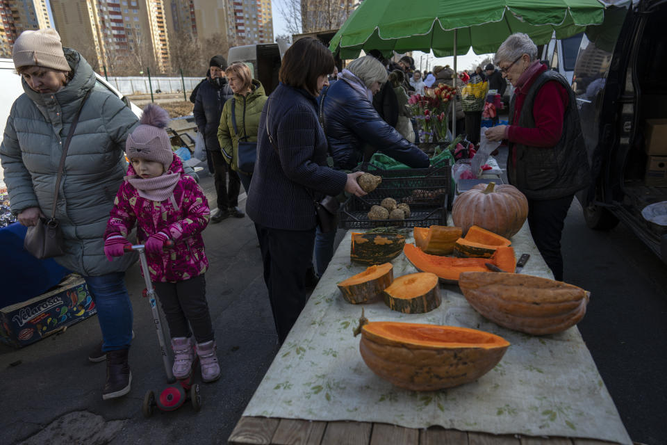 People buy vegetables in a street market in Kyiv, Ukraine, Sunday, March 20, 2022. (AP Photo/Rodrigo Abd)