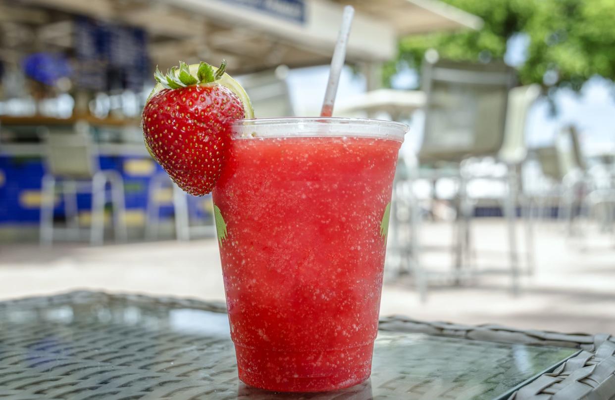 A strawberry daiquiri cocktail served in a plastic cup.