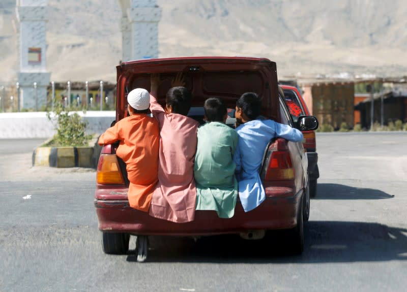 FILE PHOTO: Afghan boys travel in the back of a car during Eid al-Fitr, a Muslim festival marking the end the holy fasting month of Ramadan, amid the spread of the coronavirus disease (COVID-19), in Laghman province