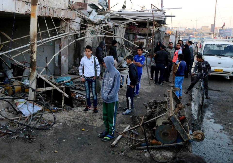 Civilians inspect the site of a car bomb attack in the eastern Ur neighborhood of Baghdad, Iraq, Tuesday, Feb. 18, 2014. A wave of explosions rocked mainly Shiite neighborhoods in Baghdad shortly after sunset on Monday, killing and wounding scores of people, said Iraqi officials. (AP Photo/Karim Kadim)