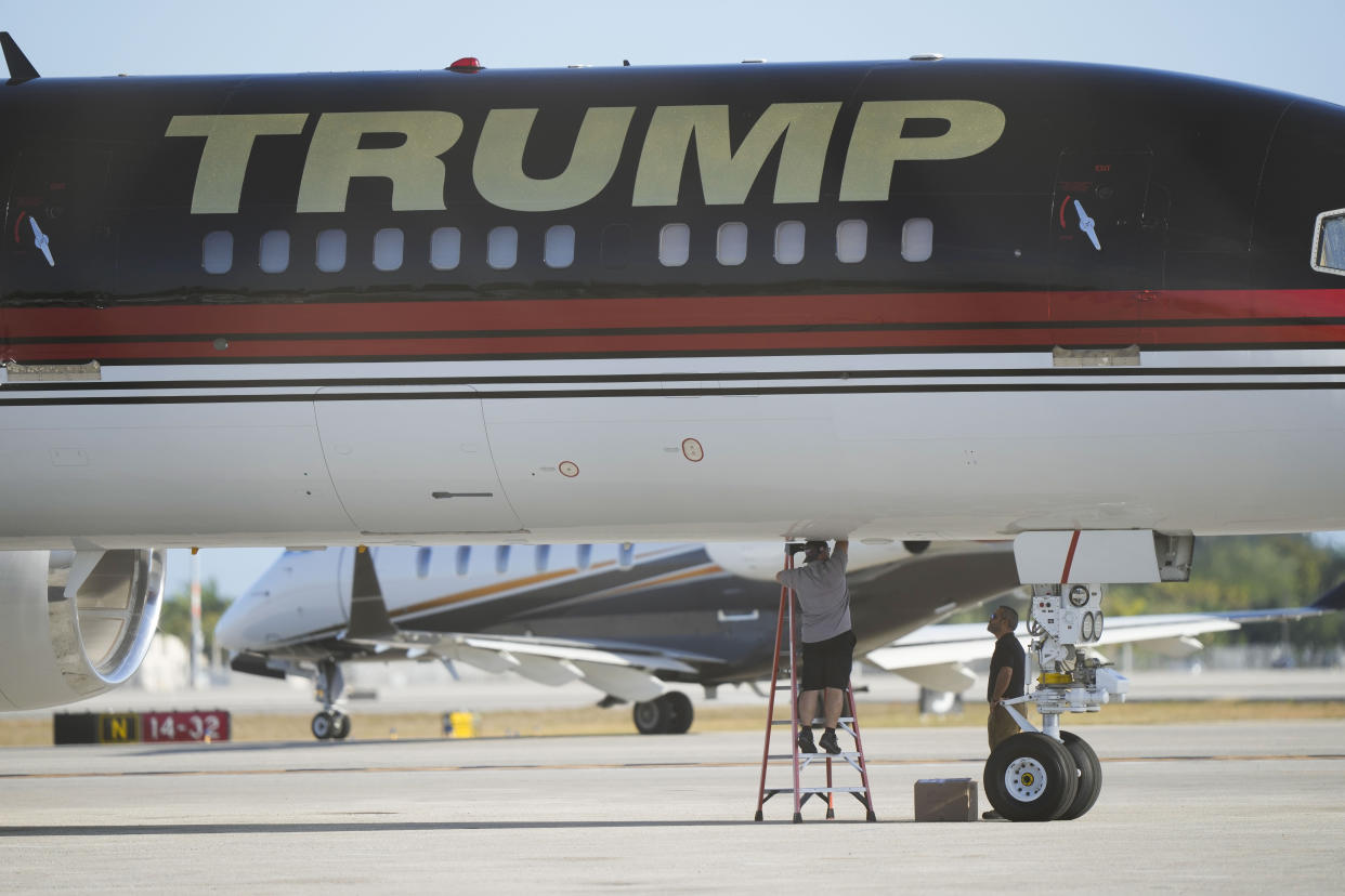 Maintenance personnel are seen working on the personal airplane of former President Donald Trump at Palm Beach International Airport in West Palm Beach, Fla., Wednesday, March 22, 2023. (AP Photo/Gerald Herbert)