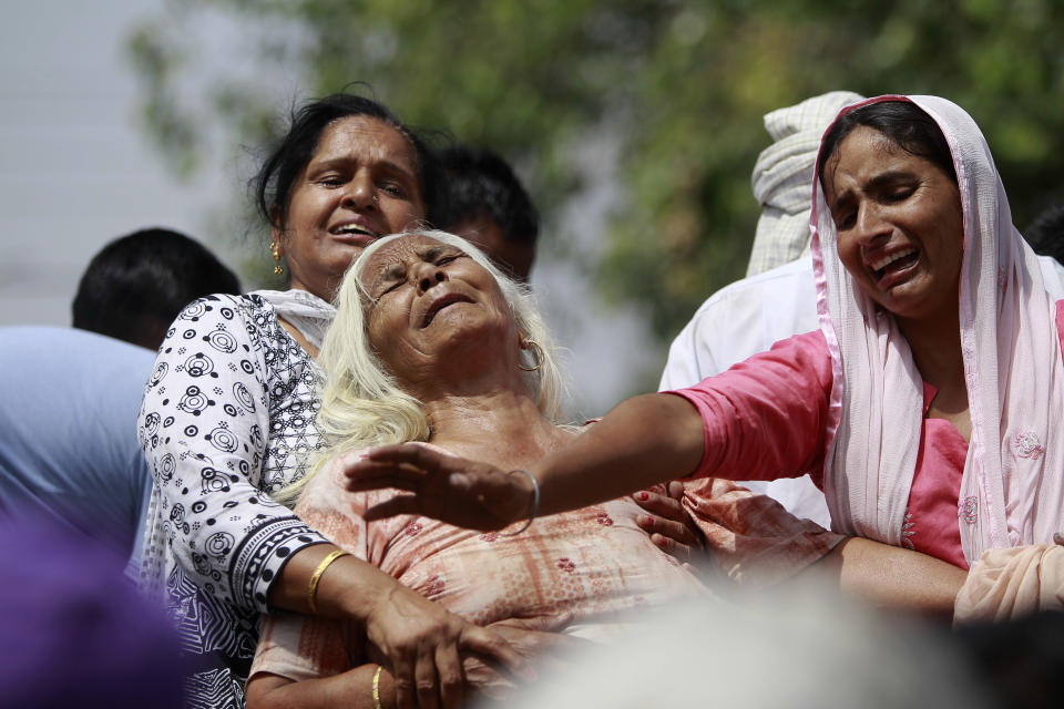 FILE - In this May 18, 2018, file photo, Indian women wail near the bodies of relatives, victims of cross-border firing, as they block a road during a protest in Ranbir Singh Pura, Jammu and Kashmir state, India. The Line of Control, a highly militarized de facto border that divides the disputed region between the two nuclear-armed rivals India and Pakistan, and a site of hundreds of deaths, is unusually quiet after the two South Asian neighbors agreed in February, 2021, to reaffirm their 2003 cease-fire accord. (AP Photo/Channi Anand, File)