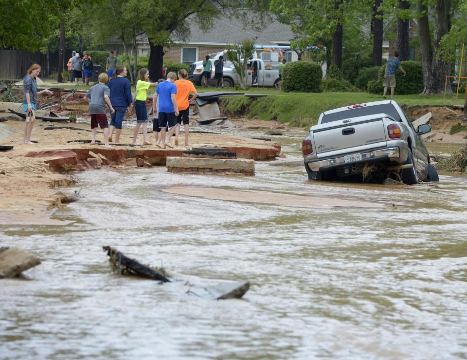 Residents walk near a truck stuck in deep water and mud on Piedmont Street after flood-water damage caused by torrential rains in Pensacola, Fla., Wednesday, April 30, 2014. (AP Photo/G.M. Andrews)