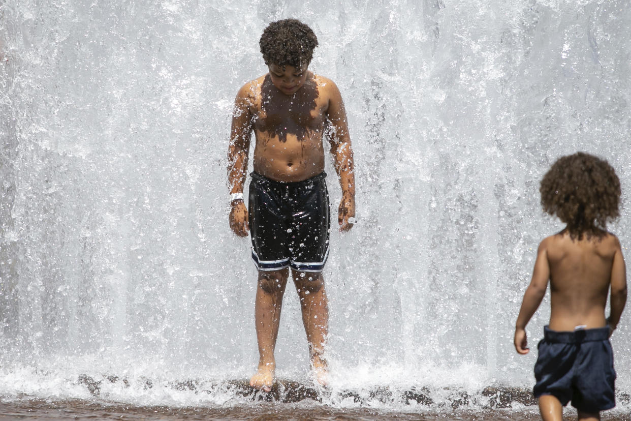 Children cool off in the Salmon Street Springs fountain in downtown Portland, Ore., as a spring heat wave sweeps across the metro area, Saturday, May 13, 2023. (Sean Meagher/The Oregonian via AP)