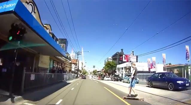 The skater crosses the busy road oblivious to the approaching car. To the left of the image, it is clear the driver has a green light. Source: YouTube/ Dash Cam Owners Australia