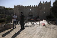 An Israeli police officer speaks with a Palestinian man during the current nationwide lockdown due to the coronavirus pandemic outside the Damascus Gate in Jerusalem's old city, Tuesday, Sept. 29, 2020. (AP Photo/Sebastian Scheiner)