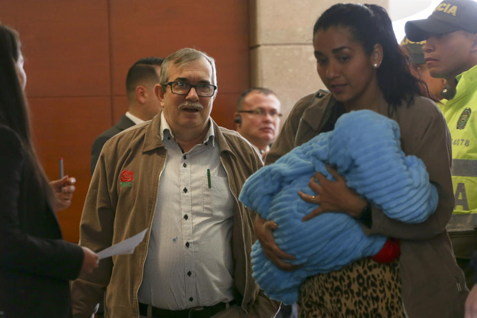 Accompanied by his wife Johana Castro and their child, former rebel leader commander Rodrigo Londono arrives to appear before Colombia's special peace tribunal to testify in an ongoing probe of the rebels' role in civilian kidnappings in Bogota, Colombia, Monday, Sept. 23, 2019. Londono, also know by his alias Timochenko, was the FARC's top military commander and now heads its legal political party. (AP Photo/Ivan Valencia)