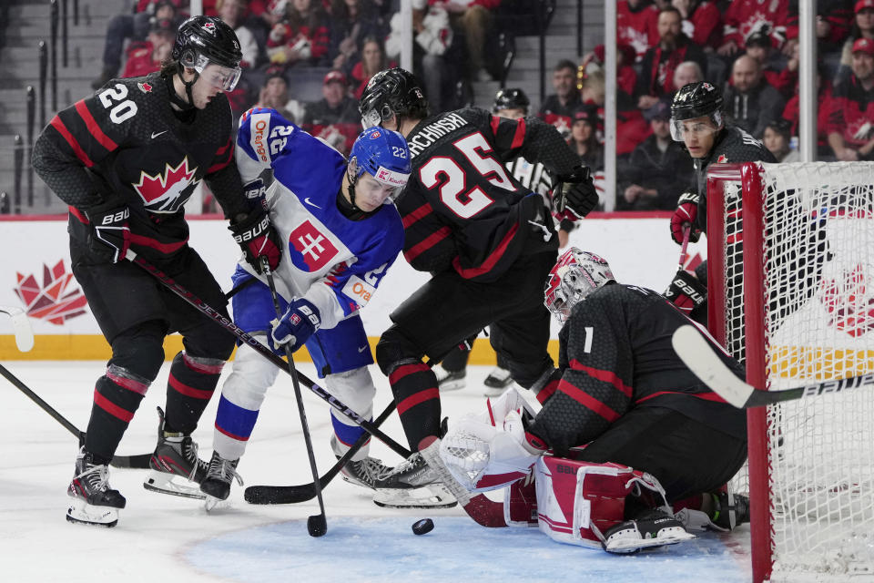 Canada goaltender Thomas Milic, right, makes a save against Slovakia's Alex Ciernik, second from left, during third-period IIHF world junior hockey championship quarterfinals action in Halifax, Nova Scotia, Monday, Jan. 2, 2023. (Darren Calabrese/The Canadian Press via AP)