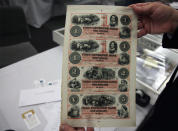 Dr. Robert Schwartz holds a sheet of banknotes issued by the Corn Exchange Bank of Nebraska.