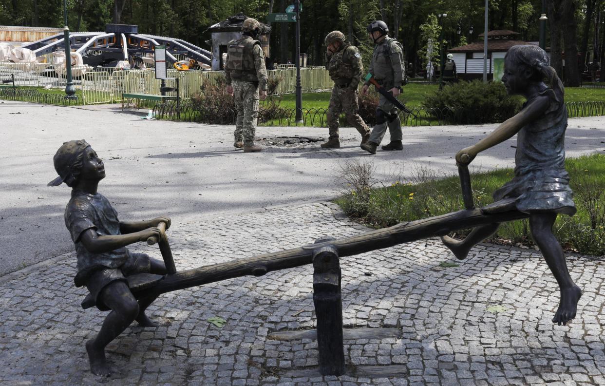 Ukrainian troops inspect damage from a Russian rocket in Maxim Gorky Central Park.