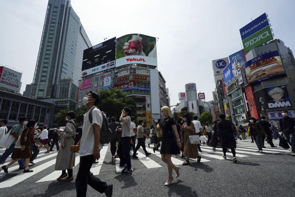 People wearing protective masks to help curb the spread of the coronavirus walk along a pedestrian crossing Friday, May 14, 2021, in Tokyo. The Japanese capital confirmed more than 850 new coronavirus cases on Friday. (AP Photo/Eugene Hoshiko)