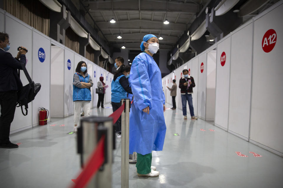 A worker stands outside rows of injection booths during a COVID-19 vaccination session for resident foreign journalists at a vaccination center in Beijing, Tuesday, March 23, 2021. Chinese medical firm Sinovac said its COVID-19 vaccine is safe in children ages 3-17, based on preliminary data, and it has submitted the data to Chinese drug regulators. State-owned Sinopharm, who has two COVID-19 vaccines, is also investigating the effectiveness of its vaccines in children. (AP Photo/Mark Schiefelbein)