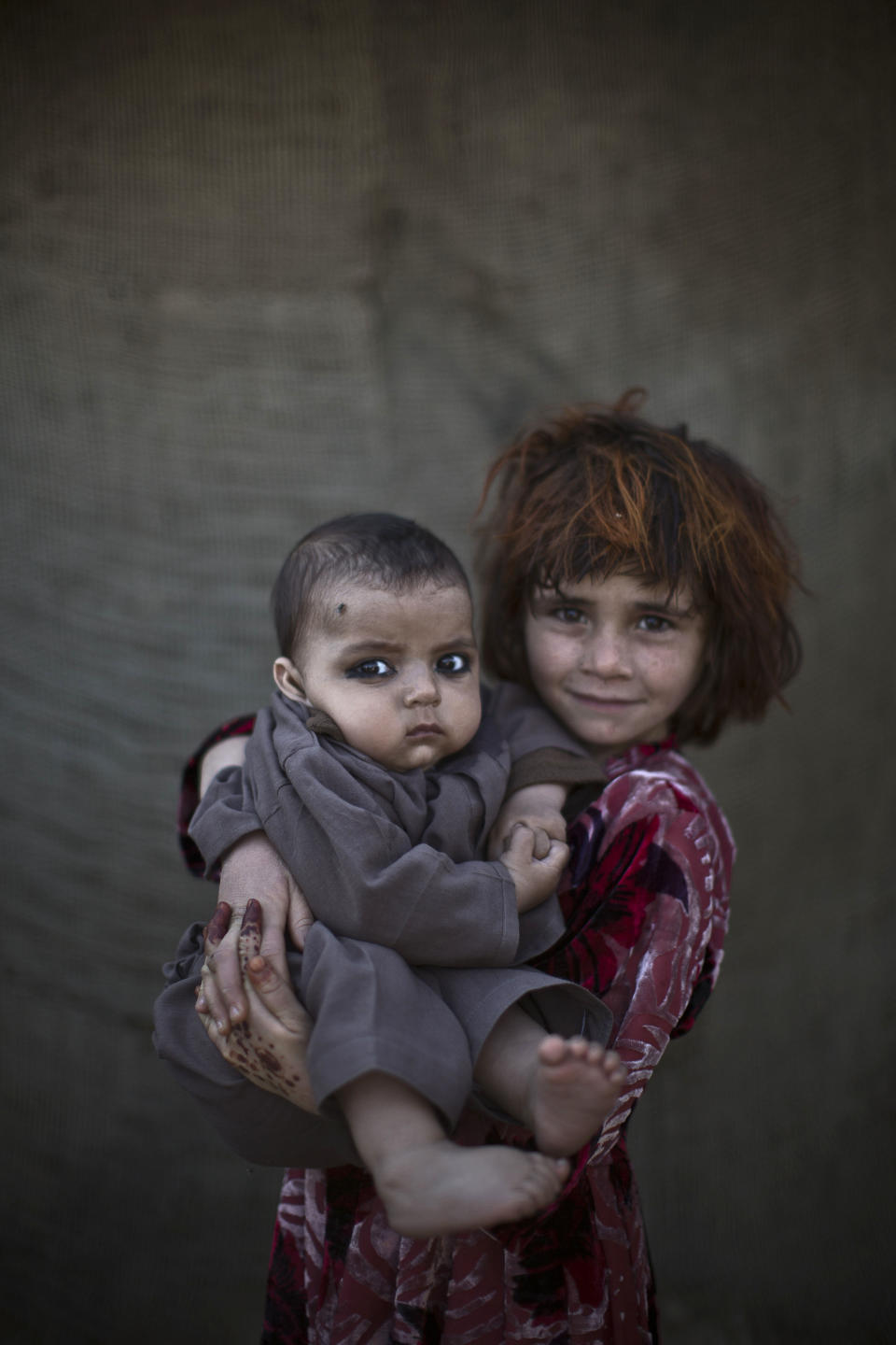 In this Monday, Jan. 27, 2014 photo, Afghan refugee girl, Khalzarin Zirgul, 6, holds her cousin, Zaman, 3 months, as they pose for a picture, while playing with other children in a slum on the outskirts of Islamabad, Pakistan, Monday, Jan. 27, 2014. For more than three decades, Pakistan has been home to one of the world’s largest refugee communities: hundreds of thousands of Afghans who have fled the repeated wars and fighting their country has undergone. Since the 2002 U.S.-led invasion of Afghanistan, some 3.8 million Afghans have returned to their home country, according to the U.N.’s refugee agency. (AP Photo/Muhammed Muheisen)