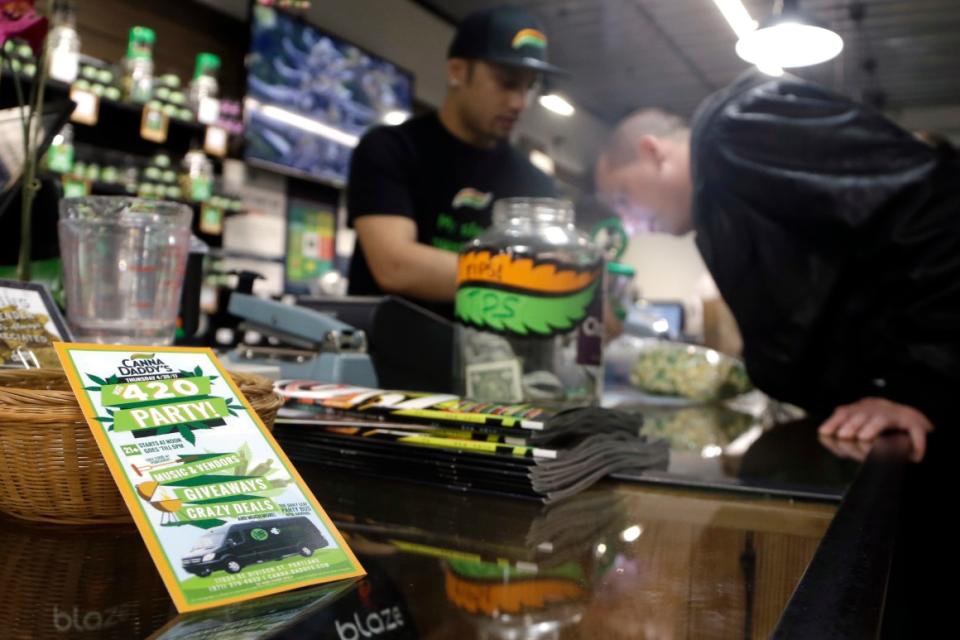 A cannabis dispensary customer smells a marijuana sample from a budtender at CannaDaddy's Wellness Center marijuana dispensary in Portland, Ore.