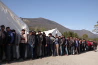 Migrants wait in line to receive aid from the Red Cross at the Vucijak refugee camp outside Bihac, northwestern Bosnia, Monday, Oct. 21, 2019. Authorities in the town of Bihac on Monday stopped the delivery of water supplies to the Vucjak camp saying they want to draw attention to the problems in the camp set up on a former landfill and near mine fields from the 1992-95 war. (AP Photo/Eldar Emric)