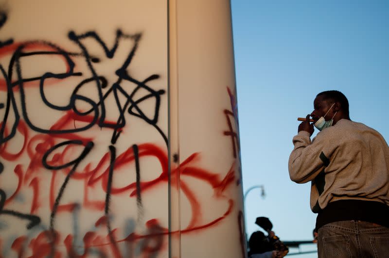 A man smokes next to graffiti during protests in Minneapolis