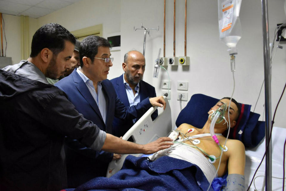 This photo released by the Syrian official news agency SANA shows Syrian Health Minister Hassan al-Ghabash, center, checking a man injured in a drone attack that hit a military graduation ceremony in Homs, Syria, Thursday, Oct. 5, 2023. Syria's health minister has raised the casualty tolls from a drone attack that hit a packed military graduation ceremony to 80 killed and 240 wounded. It was one of the deadliest attacks on the Syrian army recently, with its conflict now in its thirteenth year. (SANA via AP)