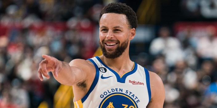 استفن کاری لبخند می زند و در طول بازی پیش فصل Warriors در سال 2022 به جلو اشاره می کند.