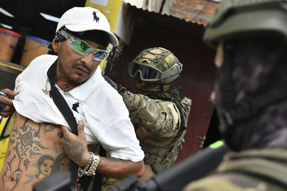 Un militar revisa la espalda de un hombre, comprobando sus tatuajes, en un control en Portoviejo, Ecuador, el jueves 11 de enero de 2024. El presidente Daniel Noboa decretó el lunes un estado de excepción tras un repunte de la violencia, una decisión que permite a las autoridades suspender derechos ciudadanos y movilizar militares para seguridad. (AP Foto/Ariel Ochoa)