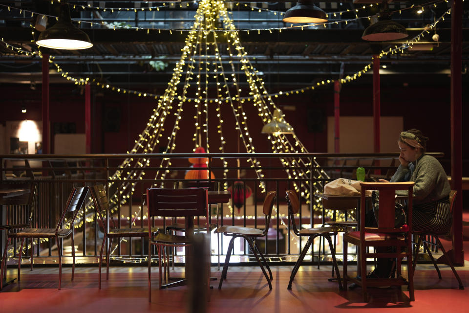 A woman sits at the Other Place theater, in Stratford-upon-Avon, Warwickshire, England, Tuesday, Feb. 28, 2023. The foyer of the Other Place theater in Shakespeare's birthplace of Stratford-upon-Avon is a cozy refuge from winter. One day a week the theater becomes a "warm hub," set up by the Royal Shakespeare Company to welcome people who may be struggling to heat their homes because of sky-high energy prices. (AP Photo/Kin Cheung)