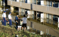 People look at an apartment building with its first floor under water in the residential area hit by Typhoon Hagibis, in Kawasaki, near Tokyo, Sunday, Oct. 13, 2019. Rescue efforts for people stranded in flooded areas are in full force after a powerful typhoon dashed heavy rainfall and winds through a widespread area of Japan, including Tokyo.(Kyodo News via AP)