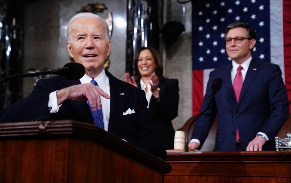 Joe Biden is applauded by Kamala Harris, the vice-president, as Mike Johnson, the Republican Speaker of the House, looks on