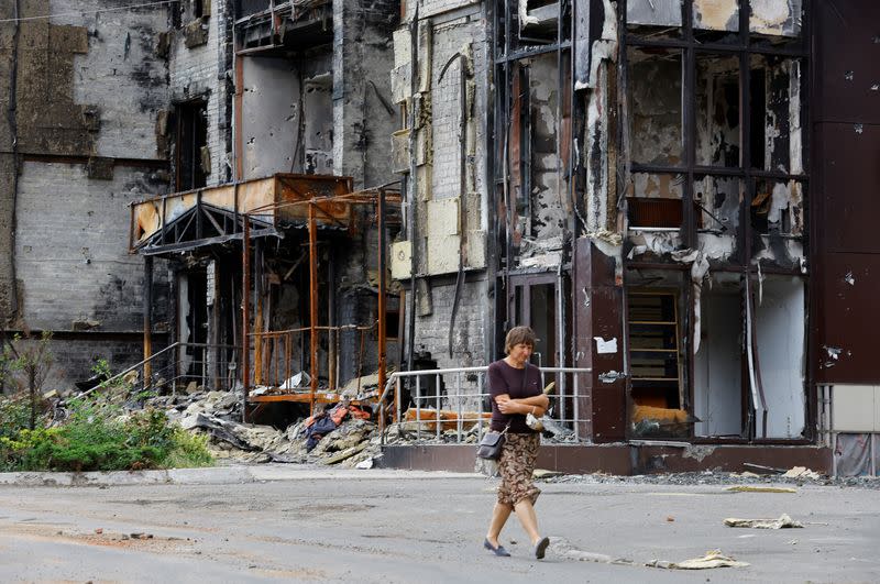 A woman walks near a damaged building in Mariupol