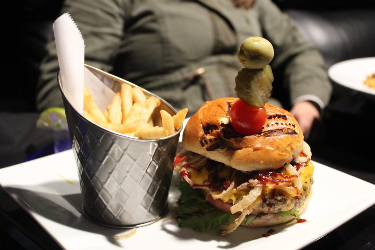 A Barbecue Burger —  house-blend burger, aged cheddar, barbecue sauce, crispy onions, lettuce, red onion and sweet and spicy pickle chips — is served with fries at Screen Suites in Akron.