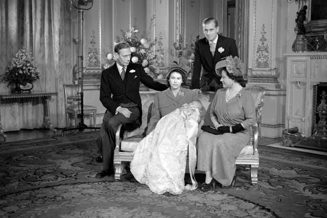 Prince Charles sleeps in the arms of his mother, Princess Elizabeth, after his christening at Buckingham Palace. Looking on are, left, King George VI, the Duke of Edinburgh, and Queen Elizabeth