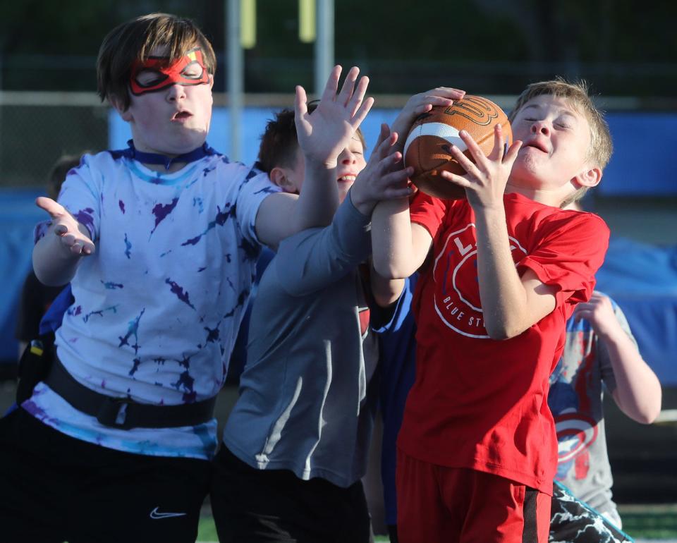 Graham Baldridge, right, catches a ball thrown to him by Lake High School football players on May 9 during Reading Under the Lights at Blue Streak Stadium in Lake Township. The event promoted reading and took place on the football field.