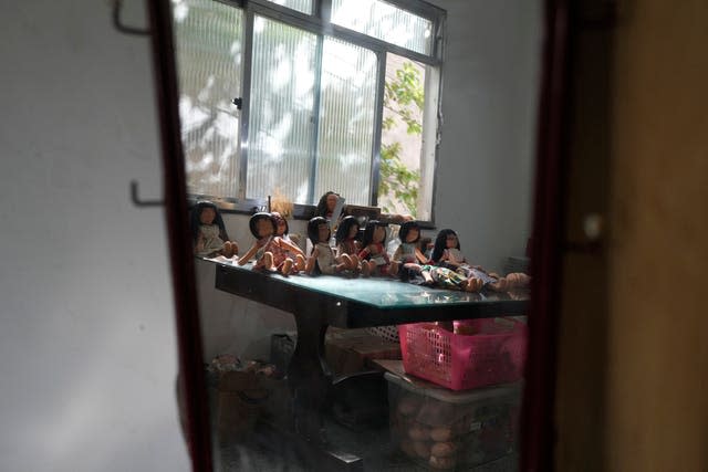 Dolls bearing faces and body paints of different indigenous groups are displayed on a table at a sewing workshop in Rio de Janeiro, Brazil 