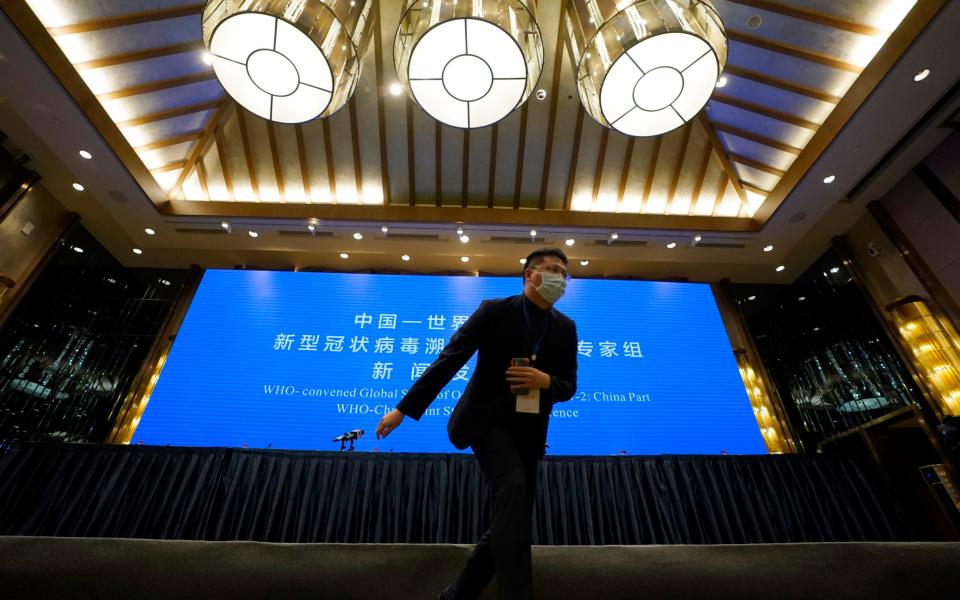 A Chinese journalist walks past the stage set for WHO-China Joint Study Press Conference - Ng Han Guan/AP