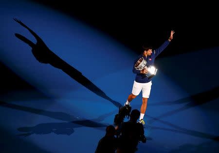 Serbia's Novak Djokovic waves as he walks with the men's singles trophy after winning his final match against Britain's Andy Murray at the Australian Open tennis tournament at Melbourne Park, Australia, January 31, 2016. REUTERS/Jason Reed