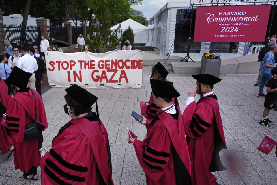 Harvard University students pass protestors while filing into Harvard Yard for commencement at Harvard University, Thursday, May 23, 2024, in Cambridge, Mass. (AP Photo/Charles Krupa)