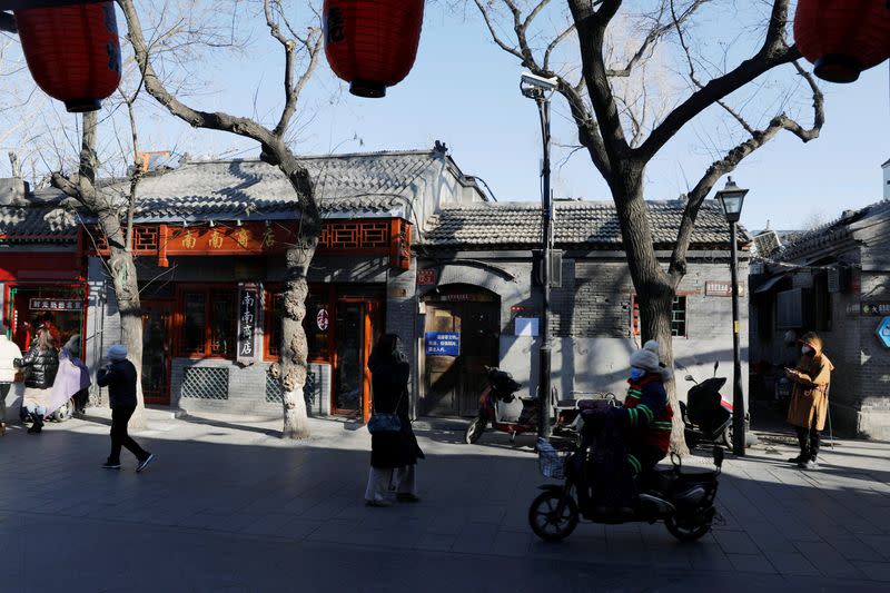 People wearing protective masks walk along Nanluoguxiang alley following the coronavirus disease (COVID-19) outbreak in Beijing