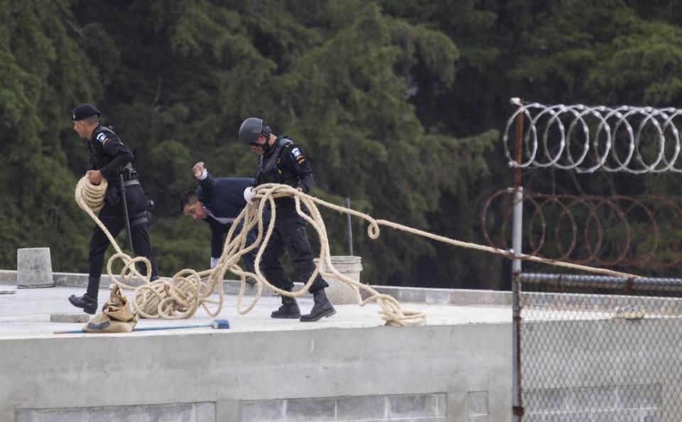 Police carry a rope for an operation to rescue four hostages during a prison riot at the Centro Correccional Etapa II reformatory in San Jose Pinula, Guatemala, Monday, March 20, 2017. Using tear gas and guns, police entered the jail and successfully freed four jail guards, following a riot that broke out Sunday during which two jail monitors were killed, according Interior Minister Francisco Rivas. (AP Photo/Moises Castillo)