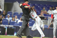 Washington Nationals' CJ Abrams (5) runs into the home plate umpire as he scores on a wild throw by Miami Marlins pitcher Andrew Nardi during the seventh inning of a baseball game, Monday, April 29, 2024, in Miami. (AP Photo/Lynne Sladky)
