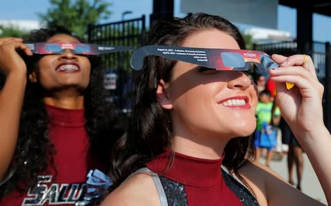 Cheerleaders use solar viewing glasses - Credit: Reuters 