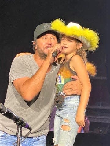 Lancaster resident Jemma Hill, 9, sings with country artist Luke Bryan Friday after he called her onstage during his concert on the Miller Family Farm near Baltimore.