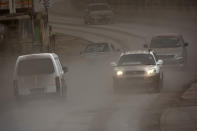 Vehicles drive on the main Black Rock road, covered with ash coming from the St. Vincent eruption of La Soufriere volcano, on the outskirts of Bridgetown, Barbados, Sunday, April 11, 2021. (AP Photo/Chris Brandis)