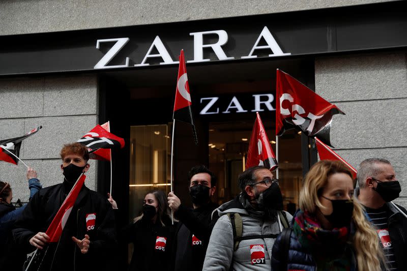 People hold flags from Spain's CGT labour union as they protest outside a Zara clothing store in Madrid