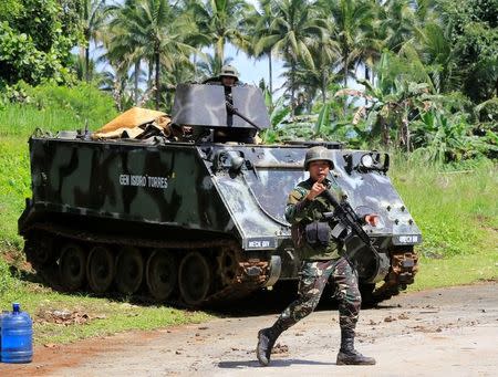 A government troop gestures as he past a armoured personnel carrier posted along a main highway of Pantar town, Lanao Del Norte, after residents starts to evacuate their hometown of Marawi city, southern Philippines May 24, 2017. REUTERS/Romeo Ranoco