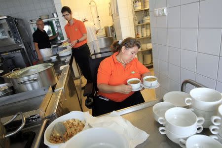 Waitress Maria Kecskemeti (in wheelchair) prepares to deliver two cups of soup in Izlelo, a restaurant in Szekszard, south of Budapest, September 22, 2014. REUTERS/Bernadett Szabo