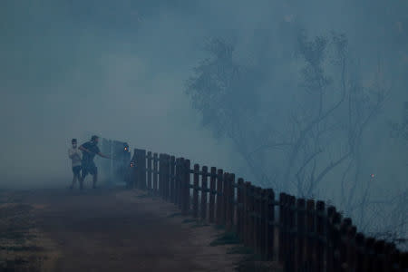 Residents use shovels and dirt to to help put out a file along a park fence during a wind driven wildfire in Orange, California, U.S., October 9, 2017. REUTERS/Mike Blake