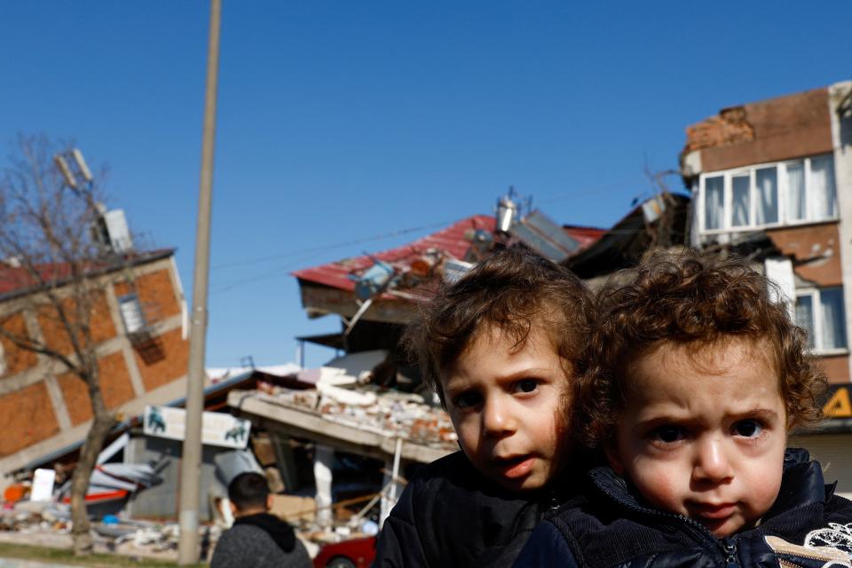 Children sit next to a damaged building in the aftermath of a deadly earthquake, in Kahramanmaras (REUTERS)