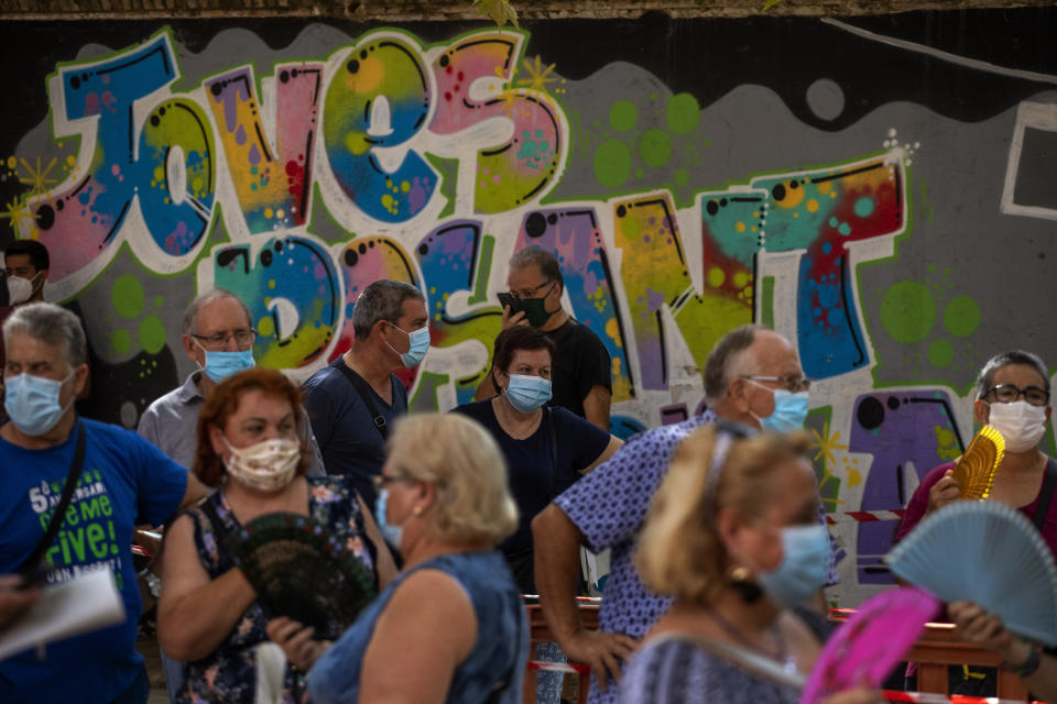 People wearing face masks queue up to be tested for COVID-19, at Vilafranca del Penedes in the Barcelona province, Spain, Monday, August 10, 2020. Spain is facing another surge in coronavirus infections not even two months after beating back the first wave. (AP Photo/Emilio Morenatti)