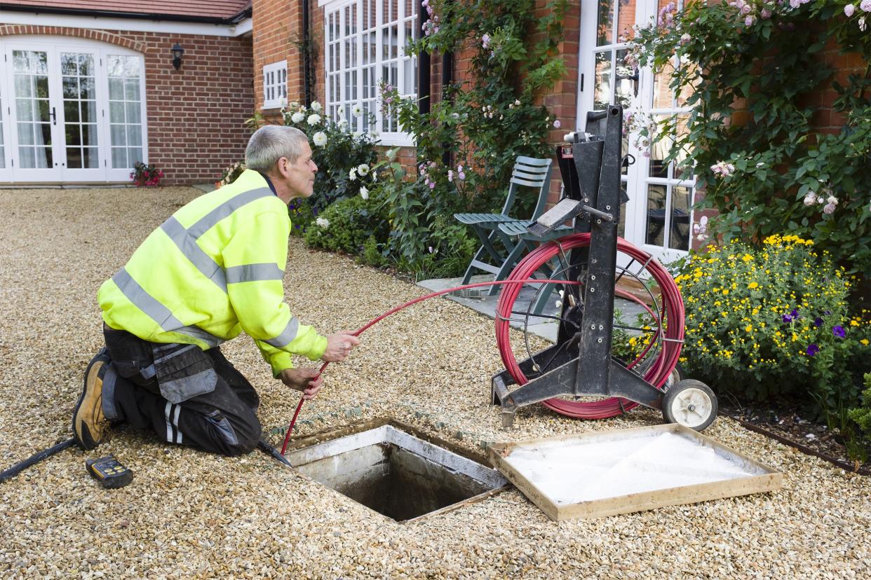 man outside unclogging drain