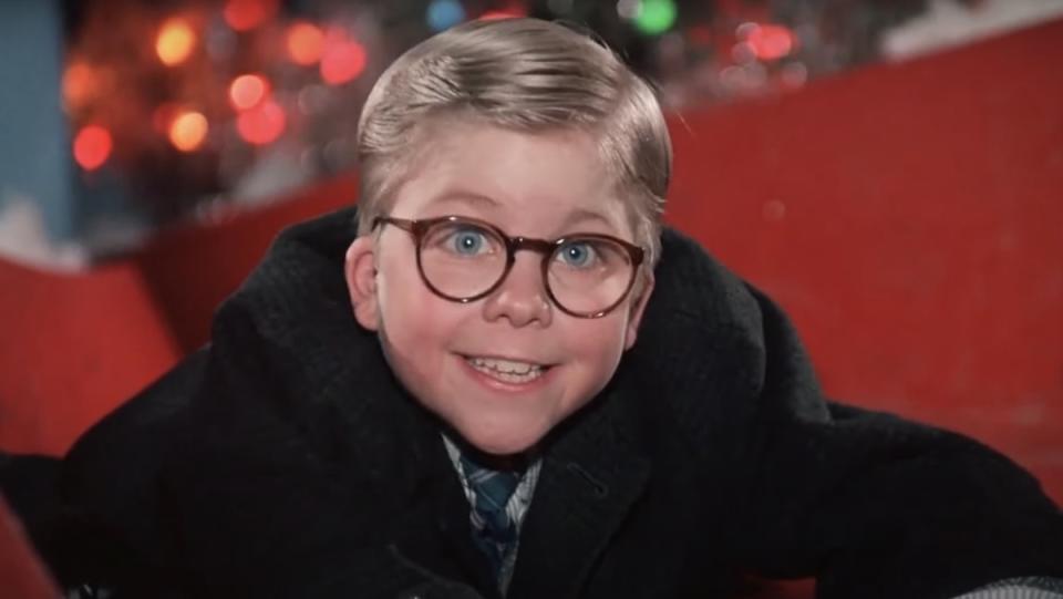 Ralphie smiles back at Santa Claus at the mall while on his belly on the slide in A Christmas Story